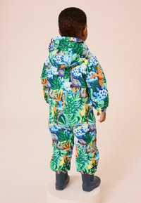 Colorful padded snowsuit featuring a dinosaur and foliage pattern in green, blue, and orange, with a hood and elastic cuffs, paired with blue boots.