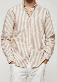 Camisa de botones a rayas en colores beige y crema; cuenta con un bolsillo, mangas largas y un cuello clásico; la tela tiene una textura suave.
