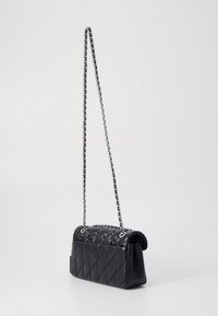 Czarna pikowana torebka o błyszczącej powierzchni, z łańcuszkowym paskiem i srebrnymi ćwiekami. Kompaktowy prostokątny kształt z zaokrąglonymi krawędziami.