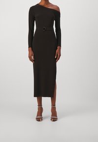 Černé šaty s dlouhým rukávem, na jedno rameno, s přiléhavým střihem, páskem v oblasti pasu a bočním rozparkem, vyrobené z hladkého, elastického materiálu.