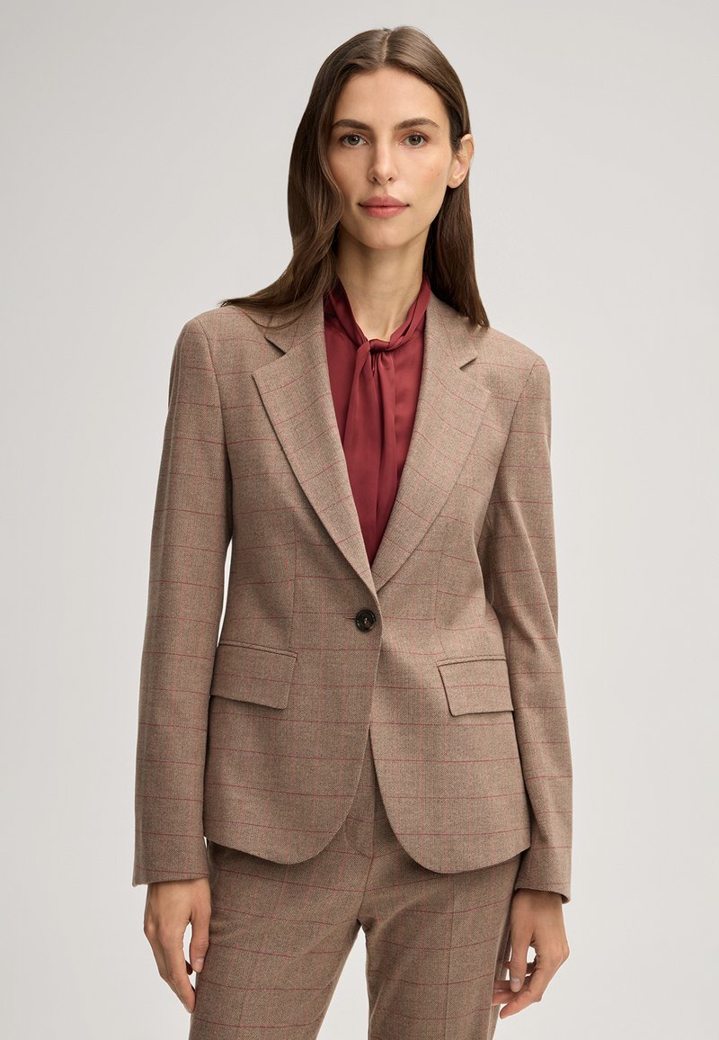 Blazer a scacchi color beige con dettagli rossi, chiusura a un bottone, rever a punta e due tasche frontali, abbinato a una blusa bordeaux.