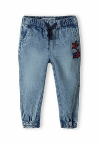 Modre denim jogger hlače z elastičnim pasom in vrvico; spredaj so okrašene z rdečo zvezdo in oznako "GIRL POWER".