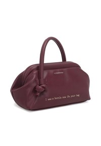 Borsa a tracolla in pelle color marrone con due manici, dettaglio annodato e testo inciso in oro che recita "Ero una bottiglia, ora sono la tua borsa." Texture liscia.