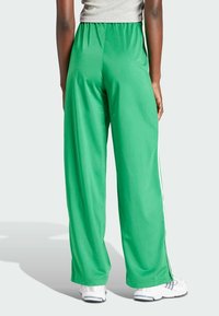 Groene sportbroeken met een ontspannen pasvorm, voorzien van een soepele textuur, witte zijstrepen en een comfortabele elastische tailleband.
