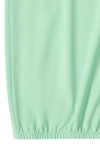 Tissu vert clair avec une texture de tissage visible, avec un ourlet élastique froncé en bas.