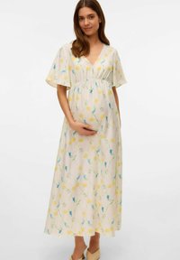 Robe de maternité florale avec un col en V, des manches courtes volantées et une taille empire ajustée. Présente des fleurs jaunes et bleues sur un fond crème.