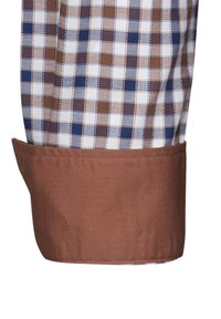 Polsino di camicia a quadri marroni con texture intrecciata; presenta quadrati blu, marroni e bianchi; tessuto marrone solido a contrasto lungo il bordo del polsino.