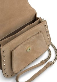 Sac bandoulière en suède beige avec une bandoulière en chaîne, comportant une poche à l'avant, des ferrures en or et des clous argentés le long des bords. L'intérieur est doublé.