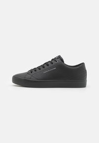 Czarne sportowe buty z gładką, syntetyczną cholewką, okrągłym noskiem, płaską gumową podeszwą i tonalnym szyciem. Posiadają logo na boku oraz sznurowane zapięcie.