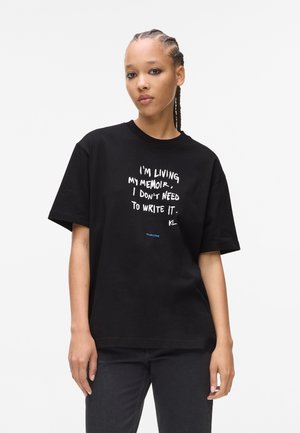 Zwarte katoenen t-shirt met korte mouwen, met een witte grafische tekstontwerp dat zegt: "Ik leef mijn memoires, ik hoef het niet op te schrijven."