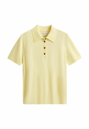 Polo à manches courtes jaune clair avec col et quatre boutons foncés sur la patte de boutonnage avant, présenté sur fond blanc.