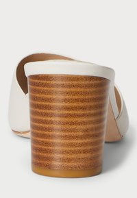 Hvit lær mule-sko med en stablet, rund treblokk-hæl vist fra baksiden på en hvit bakgrunn.