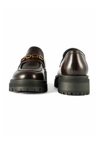 Burgundowe skórzane loafersy z akcentem w postaci złotego łańcucha, posiadające masywną czarną gumową podeszwę i teksturowany bieżnik dla lepszej przyczepności. Widok z tyłu.