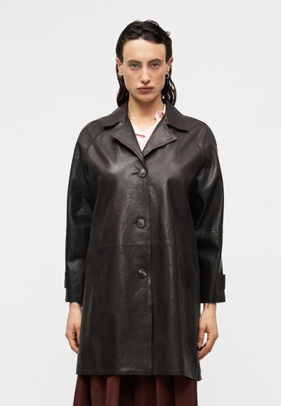Manteau en cuir marron avec un col, des boutons sur le devant, deux poches latérales et des manches en cuir noir contrastant. Texture lisse.