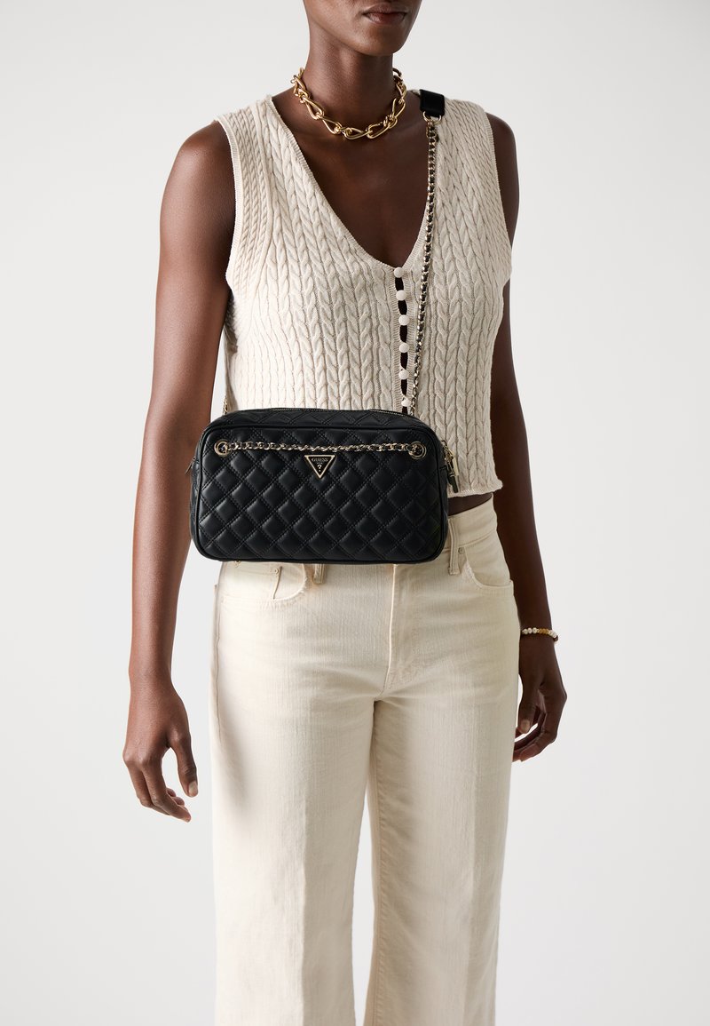 Borsa a tracolla nera trapuntata con un accento in catena dorata e logo metallico, caratterizzata da una forma rettangolare elegante e una texture liscia.