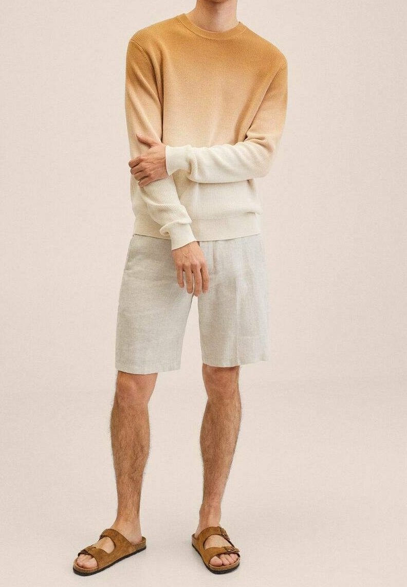 Kevyt ribbattu neule, joka siirtyy beigestä kermaan, yhdistettynä vaaleanharmaisiin pellavashortseihin ja ruskeisiin sandaaleihin, joissa on säädettävät remmit.