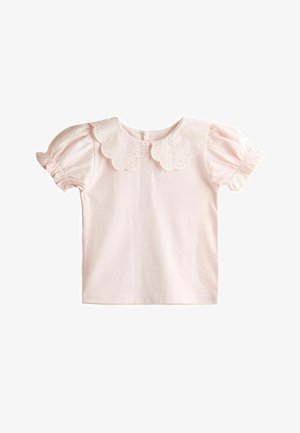 Világos rózsaszín, rövid ujjú blúz puffadt ujjakkal és hullámos szélű, lyukacsos csipkegallérral, fehér háttéren.