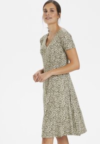 Green floral dress with a V-neck and short sleeves, featuring a light, flowy fabric and knee-length silhouette with a flared hem.
