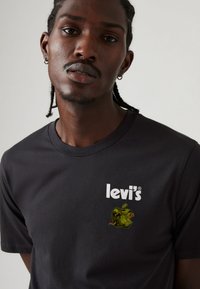 Sort bomulds t-shirt med Levi's logo og et grafisk design af et grønt æble med en orm, rund hals og korte ærmer.