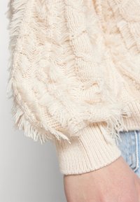 Ninjapaita vaaleassa beessissä, jossa on teksturoitu, franssitunnistettu hihansuu ja ribbireunat. Ominaisuuksina kaapelikuvio. Sopii arkivaatteeksi.