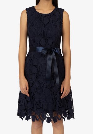 Ärmelloses marineblaues Spitzenkleid mit Blumenmuster, knielangem Saum und einem in der Taille zu einer Schleife gebundenen Satinband.