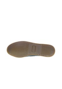 Suela de zapato de goma marrón con agarre texturizado, que presenta un borde suave y un pequeño detalle rectangular en el centro.