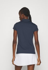 Polo shirt navy cu mâneci scurte, cu un guler clasic și o textură netedă. Asortat cu o fustă albă plisată pentru contrast.