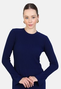 Abito lungo a maniche lunghe blu navy a coste, con scollatura rotonda e polsini svasati, che mette in mostra un tessuto liscio e texturizzato e una silhouette attillata.