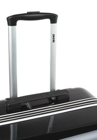 Maleta rígida negra con un mango retráctil plateado, que presenta un agarre negro y un acento blanco en el borde del zipper. Logo presente en el mango.