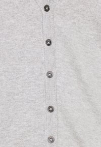 Hellgraue Strickjacke mit V-Ausschnitt, sieben schwarzen Knöpfen vorne und gerippten Details an den Kanten. Weiche Strickstruktur.