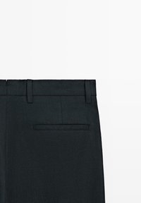 Pantaloni neri su misura con passanti per cintura e una tasca posteriore a filetto singolo sul lato destro su sfondo bianco.