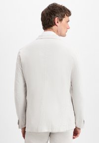 Light gray jacket with a textured fabric, single-breasted design, and notched collar, featuring stitching details and two-button cuffs.
