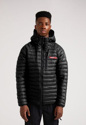 Sort polstret jakke med hætte, der har et vandret quiltet design, rød "JACKIT" mærkat på brystet og lynlåslommer. Mat finish.
