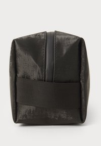 Svart rektangulær bag med en glatt, lett teksturert overflate. Har en sentral glidelås og et horisontalt svart webbing-stropp på baksiden.
