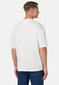 Bílá krátkosrstá tričko s krátkým rukávem, vyrobené z bavlny, s uvolněným střihem, kulatým výstřihem a jemnou texturou. Žádné viditelné vzory ani hardware.