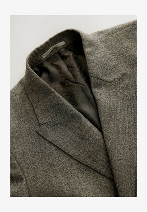 Blazer grigio in lana con un'elegante revers a collare, taschino sul petto singolo e fodera scura a motivo. Il tessuto testurizzato accentua la profondità.