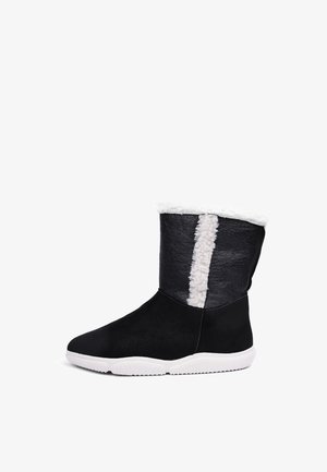 Sorte ruskindsankelstøvler med en hvid fleece-foret krave og en struktureret sort sidesektion. Sålen er hvid med et dækmønster.