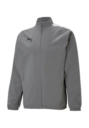 Veste coupe-vent gris avec un col montant, des poignets et un ourlet élastiques, arborant un logo noir sur la poitrine gauche. Tissu lisse et léger.