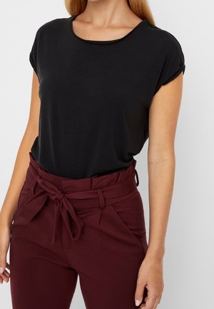 Haut noir à manches courtes avec un col rond, associé à un pantalon bordeaux taille haute avec un nœud à la taille et des poches avant.