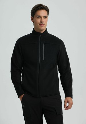 Black fleece jacket with high collar, front zip closure, and zippered chest pocket. Smooth texture and fitted design.