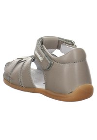 Sandale en cuir gris clair avec un design ouvert, une bride ajustable et une semelle en caoutchouc. Présente des accents cousus et des détails découpés sur les côtés.