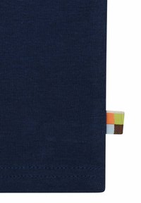 Marineblaue Stoff mit einer glatten Textur, der ein kleines mehrfarbiges Etikett am rechten Rand und flache Nähte entlang des unteren Saums aufweist.