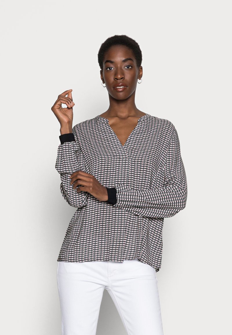 Blusa de manga longa, em V, em malha texturizada preta e branca com detalhes vermelhos, apresentando punhos canelados pretos e um corte descontraído.