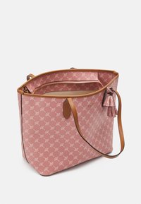 Vaaleanpunainen kangaskassi, jossa on toistuva valkoinen kuvio, vaaleat nahkaosat ja ylhäältä suljettava vetoketju. Sisältää sisäisiä osastoja ja avaimenperän.