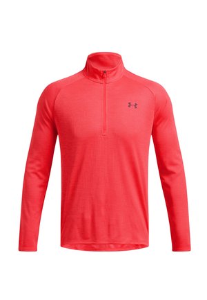 Long-sleeve coral red athletic top with quarter zip and small black Under Armour logo on the chest, displayed on white background.