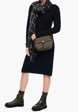 Musta ribbiletu mekko, harmaa ruutuhuivi, oliivinvihreä olkalaukku nepparilla. Oliivinvihreät nilkkasaappaat vetoketjulla ja tekstiilistä sukat.