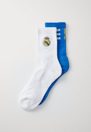 Pair of socks: one white with a round logo and ribbed texture, one blue with white stripes and yellow text, showing contrasting colors and designs.