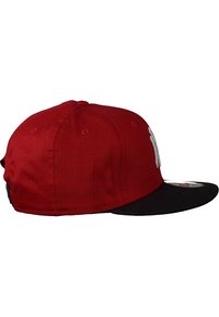 Gorra roja con visera negra, fabricada en tela. Presenta un logo bordado en blanco y agujeros de ventilación en la corona. Diseño clásico de gorra de béisbol.