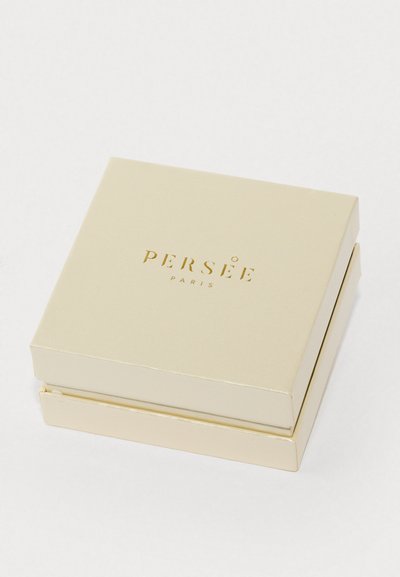 Štvorcová kovová zlatá šperkovnica s hladkým povrchom, s embosovaným nápisom "PERSÉE PARIS" na viečku.