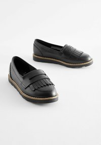 Schwarze Lederloafer mit Fransenakzenten, genähten Details und einer beigen Gummisohle. Abgerundete Spitze und flaches Design für einfaches Hineinschlüpfen.